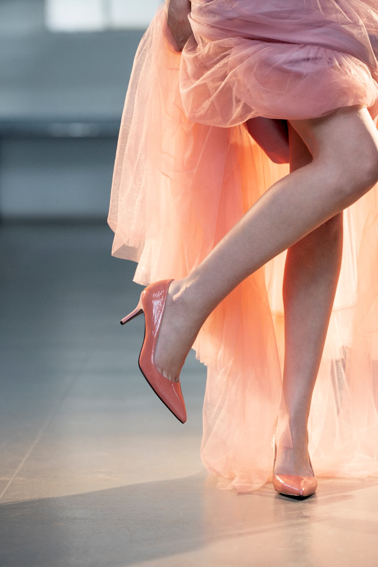 Peach patent pumps worn with a flowing tulle dress